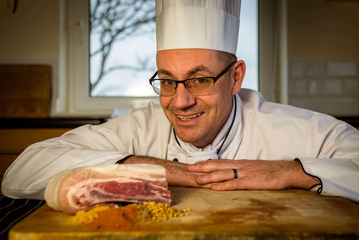 Chef Matthew Brownie pictured with piece of pork and spices